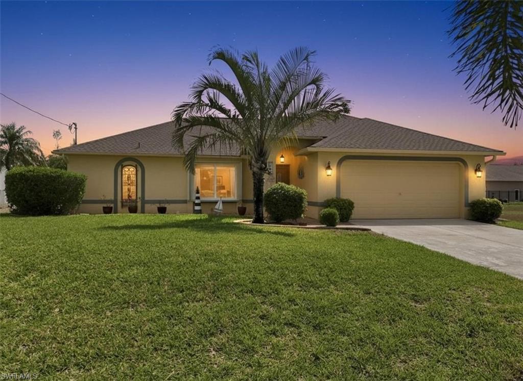 View of front of home with stucco siding, a garage, a front yard, and concrete driveway