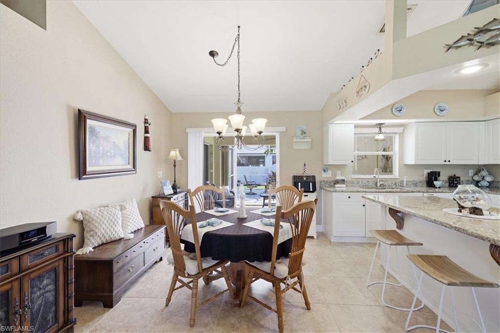 Dining room with lofted ceiling, hanging lights, and light tile patterned floors