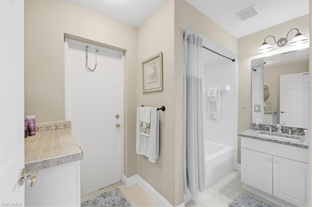 Bathroom with vanity, shower / tub combo with curtain, and light tile patterned floors