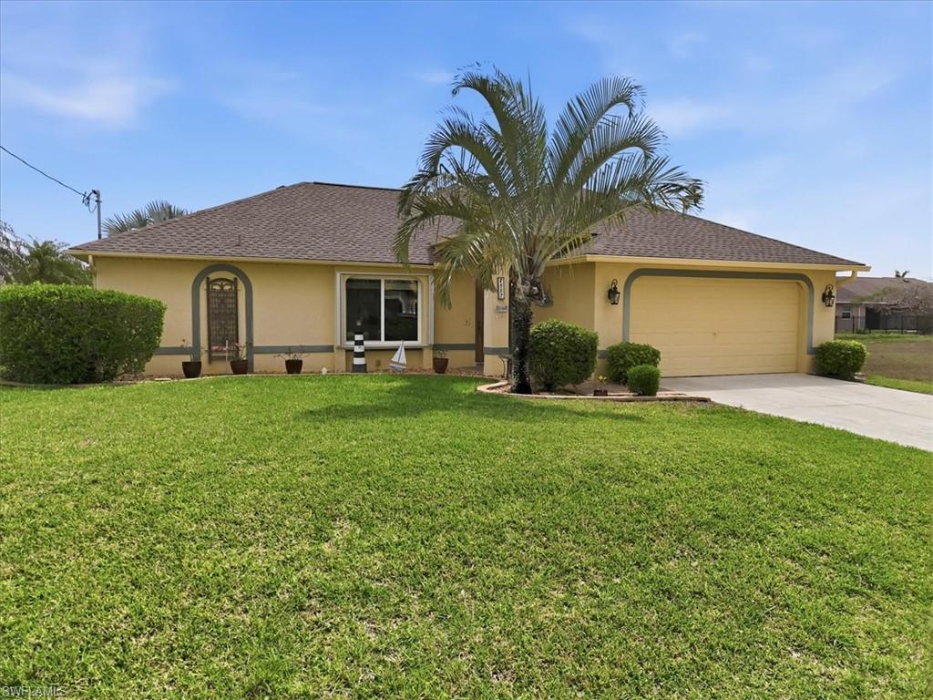 Ranch-style house featuring an attached garage, stucco siding, a front lawn, and driveway