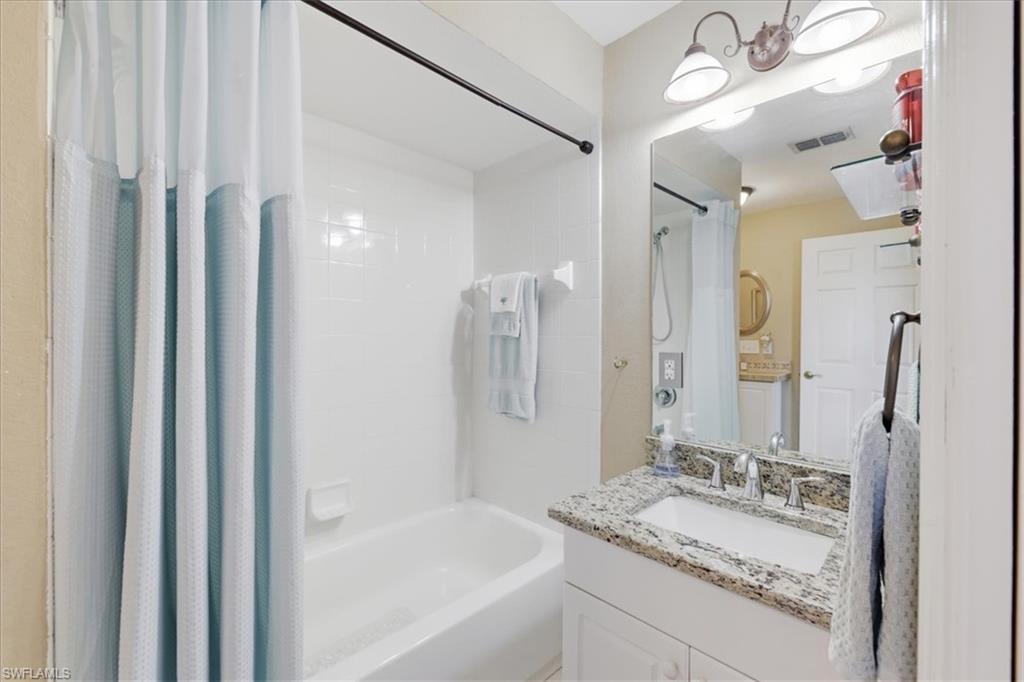 Bathroom featuring vanity and shower / bathtub combination with curtain
