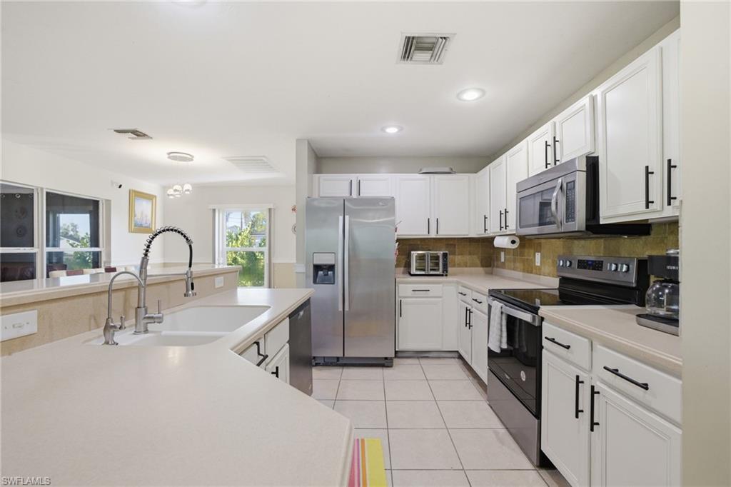 Kitchen with stainless steel appliances, light countertops, white cabinets, light tile patterned flooring, and recessed lighting
