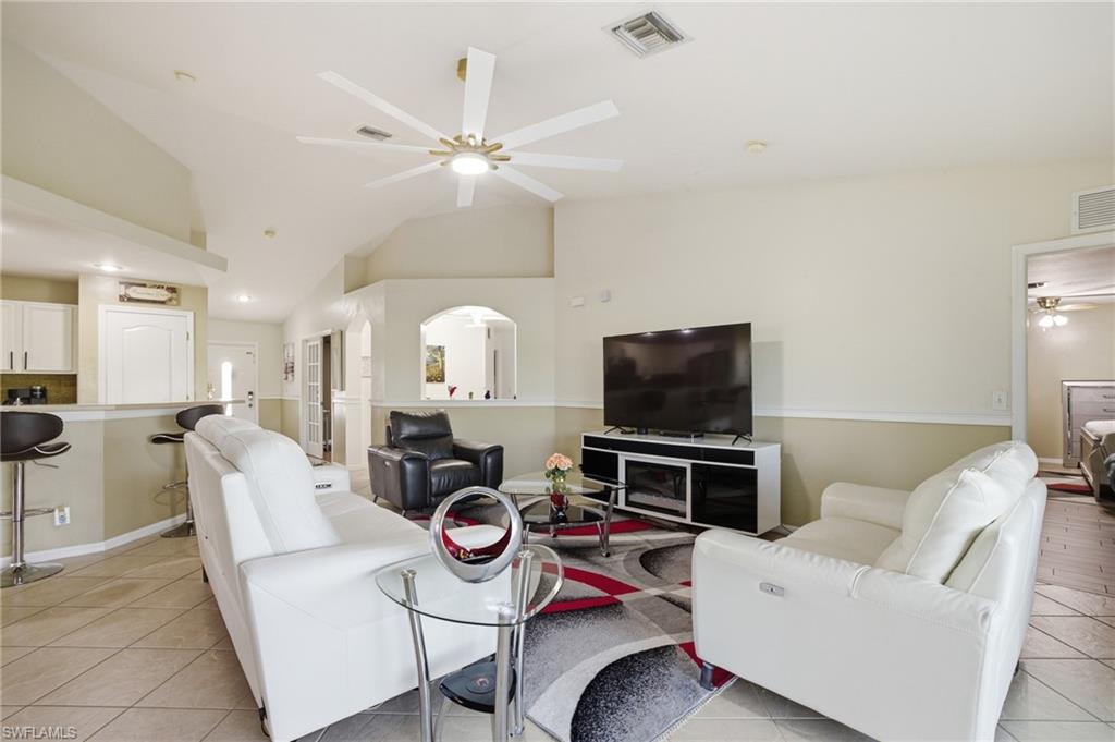 Living room with ceiling fan, light tile patterned floors, lofted ceiling, and recessed lighting
