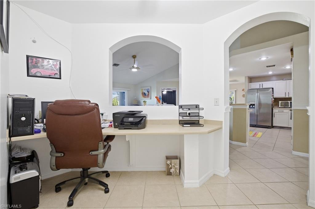 Office area with arched walkways, ceiling fan, light tile patterned flooring, vaulted ceiling, and recessed lighting