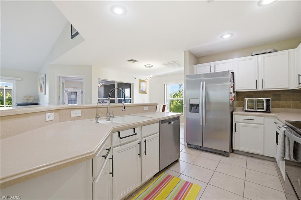 Kitchen with stainless steel appliances, white cabinets, light countertops, tasteful backsplash, and recessed lighting