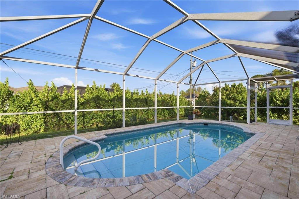 Outdoor pool with glass enclosure, a sunroom, and a patio area