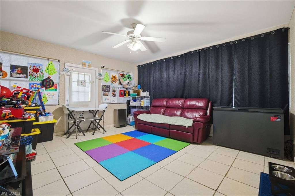 Game room with a ceiling fan and light tile patterned floors