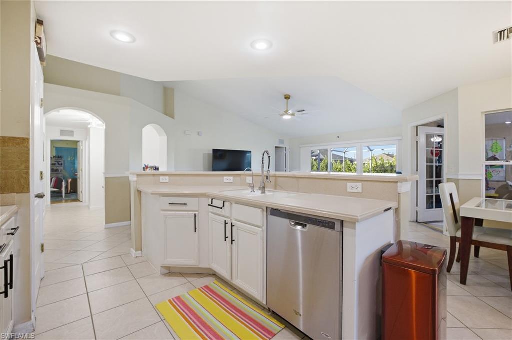 Kitchen with an island with sink, dishwasher, light countertops, vaulted ceiling, and open floor plan
