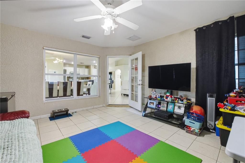 Playroom featuring a textured wall, a ceiling fan, and light tile patterned floors