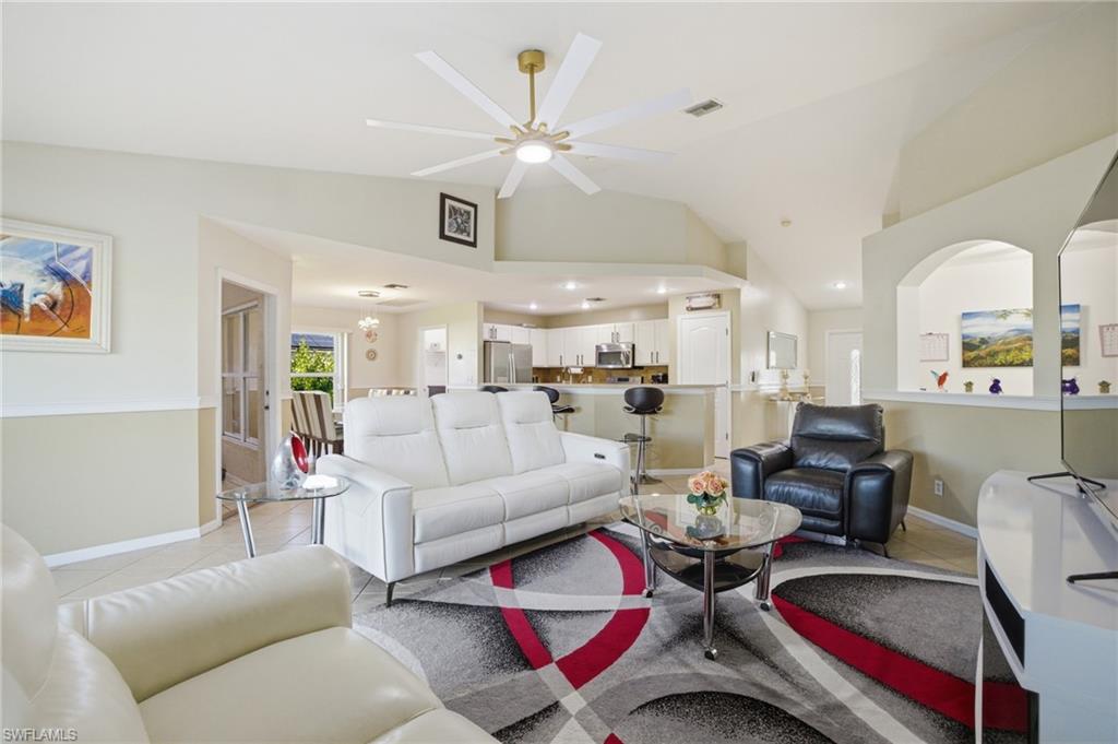 Living area with ceiling fan, light tile patterned flooring, and lofted ceiling