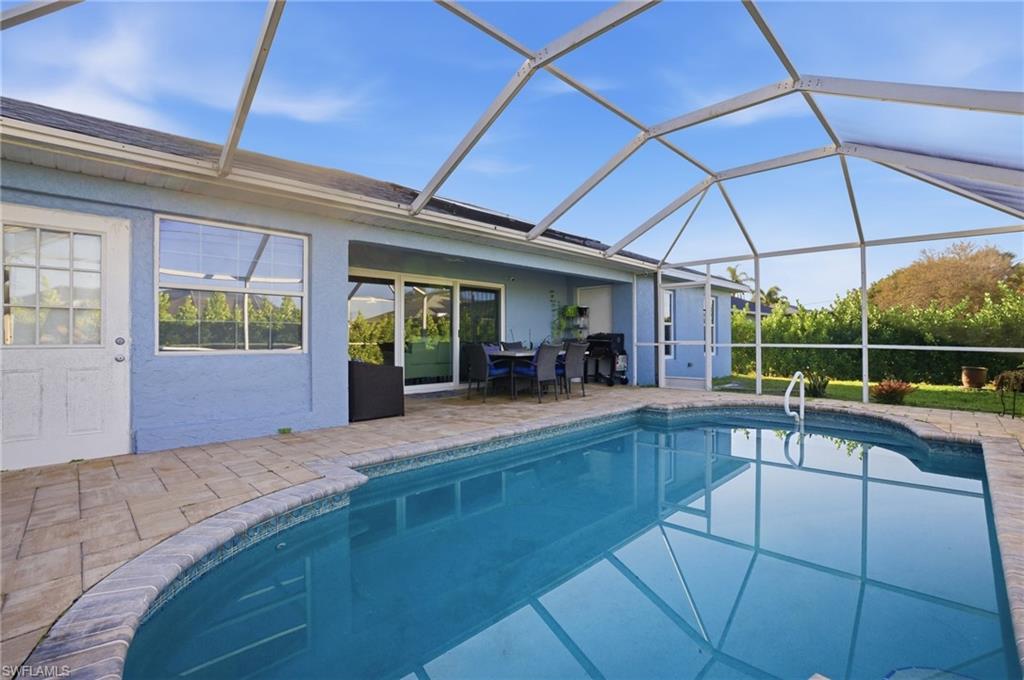 Outdoor pool featuring a sunroom, outdoor dining area, a patio area, and glass enclosure