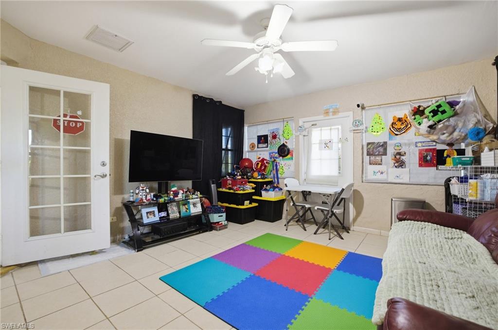Playroom with ceiling fan, light tile patterned floors, and a textured wall