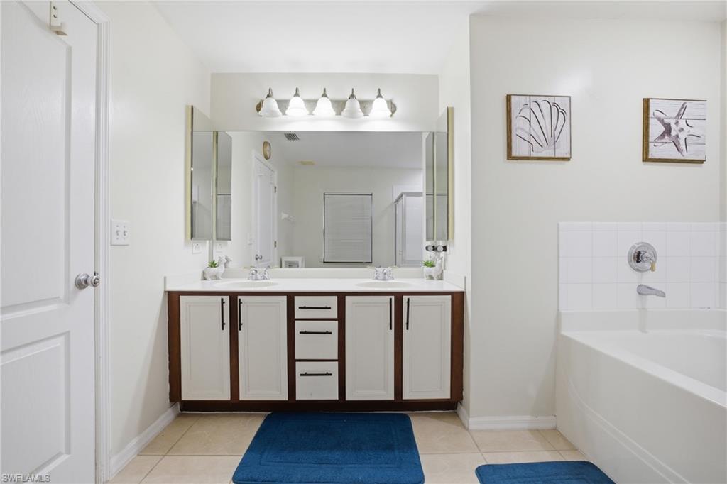 Full bath featuring double vanity, a bath, and light tile patterned floors
