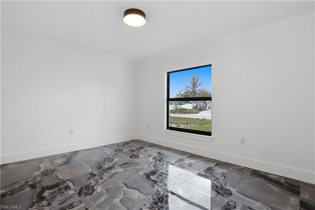 Unfurnished room with ornamental molding and light marble finish flooring