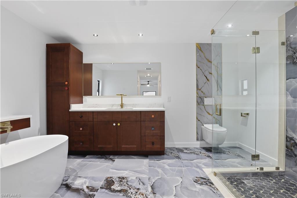 Bathroom with a marble finish shower, vanity, recessed lighting, light marble finish flooring, and a soaking tub