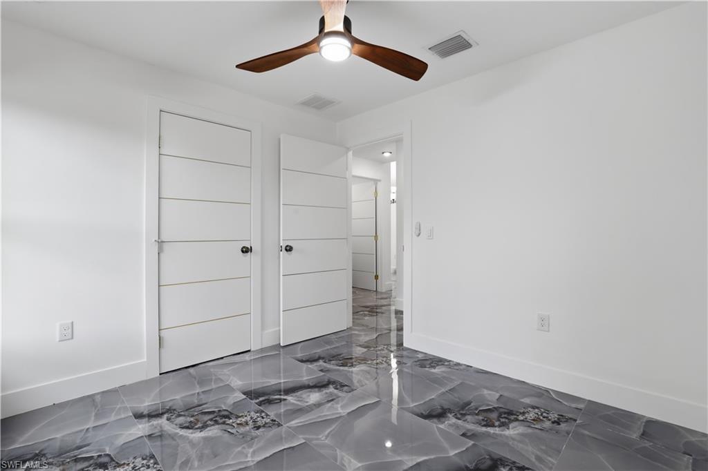 Bedroom with dark marble finish floors and ceiling fan