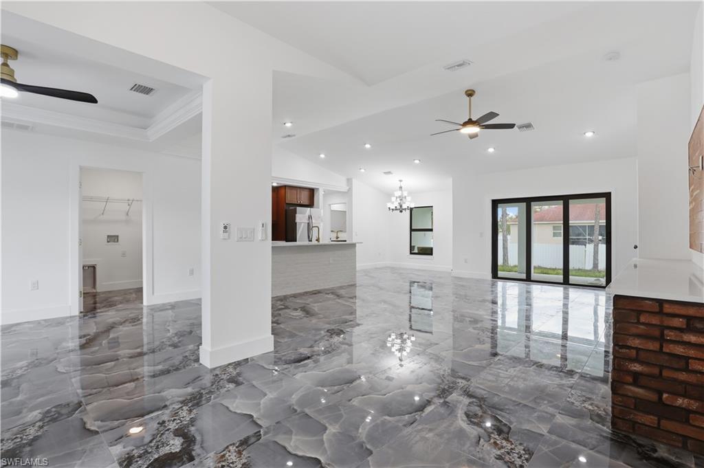 Unfurnished living room featuring a ceiling fan, marble tiled flooring, hanging lights, and lofted ceiling