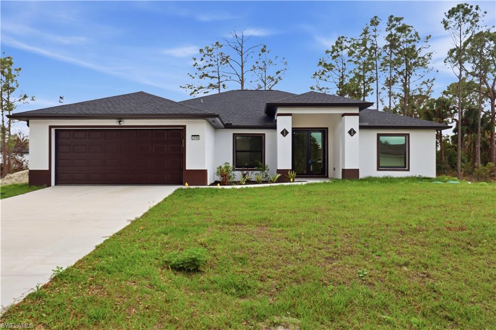 Prairie-style house featuring an attached garage, concrete driveway, a front yard, and stucco siding