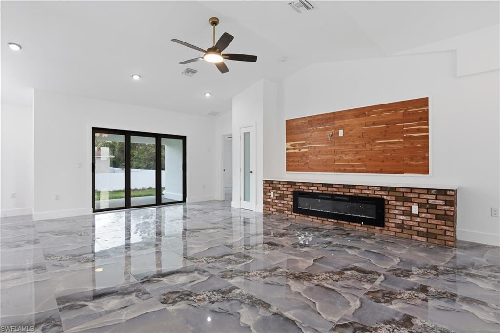 Unfurnished living room with a fireplace, a ceiling fan, marble tiled flooring, vaulted ceiling, and recessed lighting