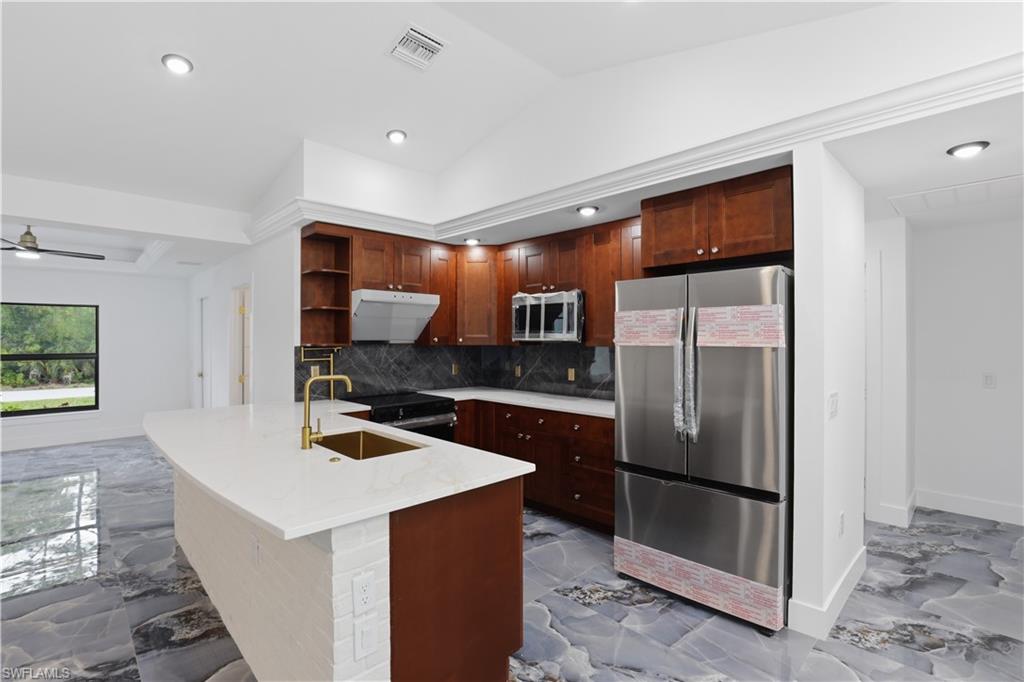Kitchen with stainless steel appliances, a peninsula, open shelves, light marble finish floors, and light stone countertops