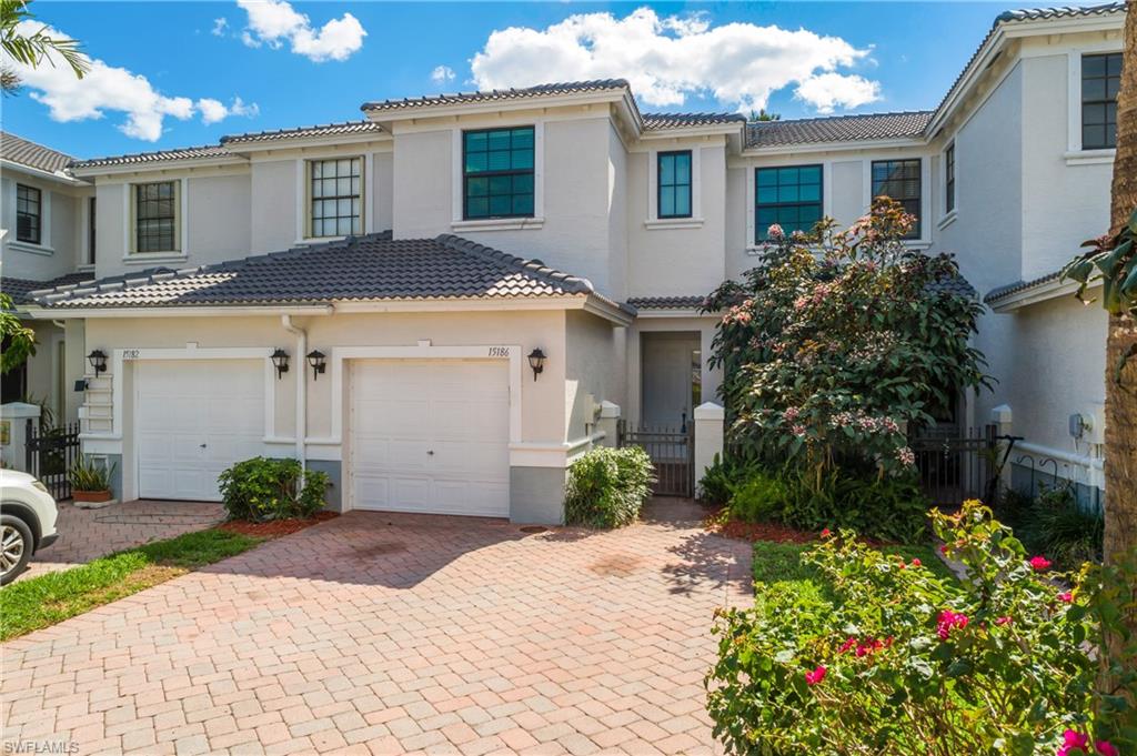 Mediterranean / spanish-style home featuring decorative driveway, a tiled roof, stucco siding, and a gate