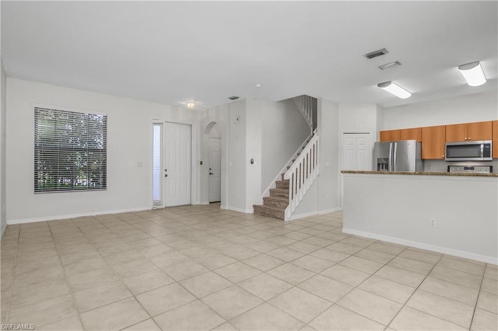 Unfurnished living room featuring stairs and arched walkways