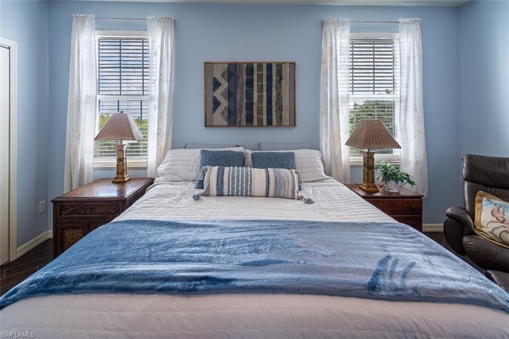 Bedroom with dark wood-style flooring and multiple windows