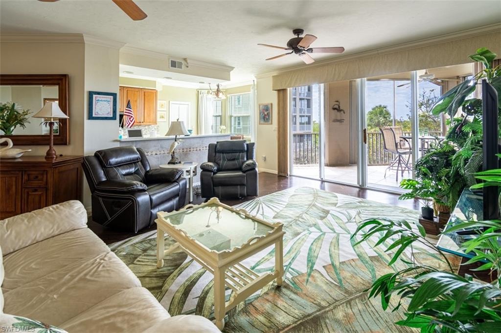 Living area featuring a ceiling fan, crown molding, plenty of natural light, a chandelier, and wood finished floors