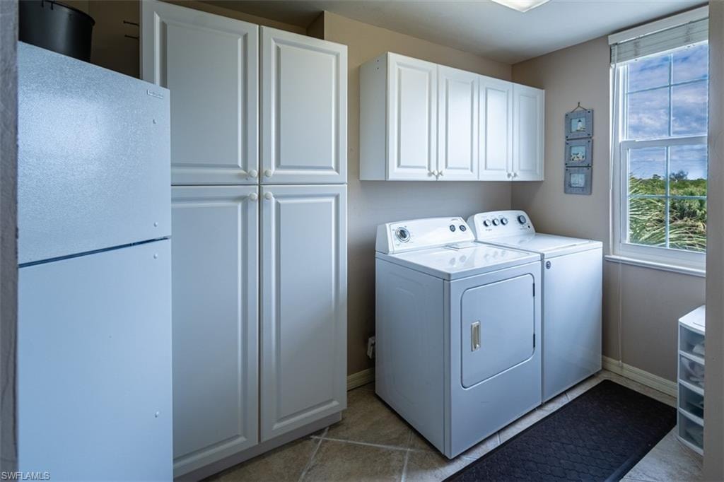 Laundry room featuring cabinet space, washing machine and clothes dryer, and light tile patterned floors