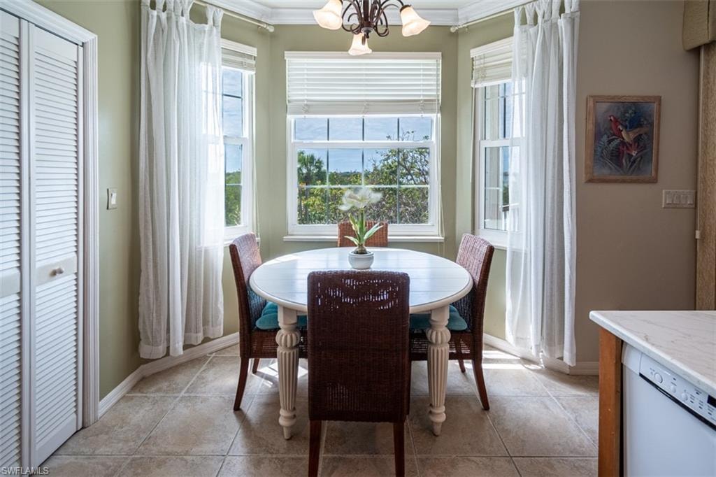 Dining room featuring suspended lighting, ornamental molding, and light tile patterned floors