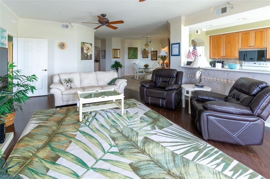Living area with ornamental molding, a ceiling fan, and dark wood-type flooring