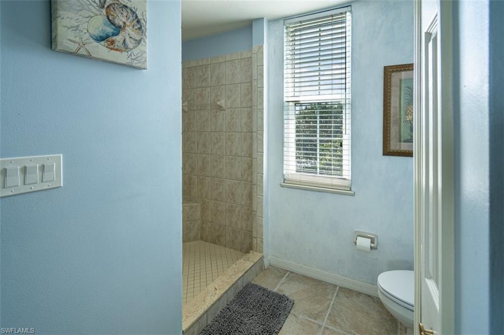Full bathroom featuring a shower stall and light tile patterned flooring
