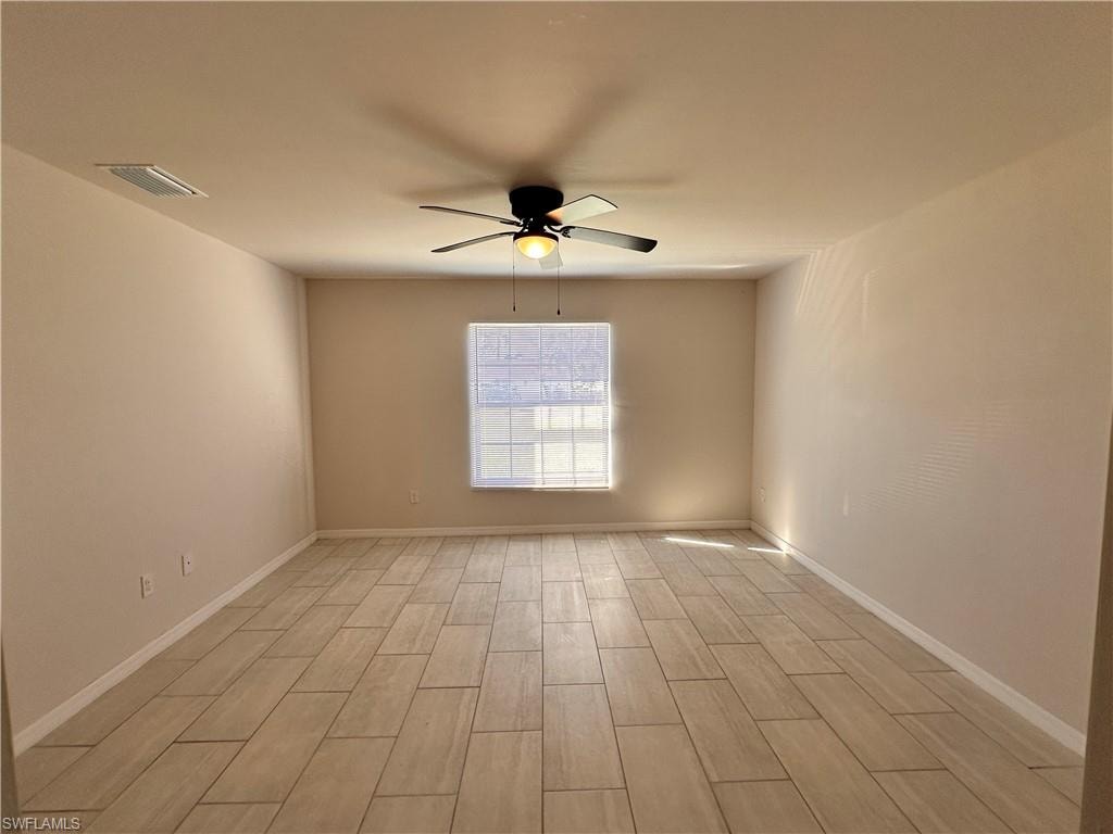Empty room with wood tiled floors and a ceiling fan