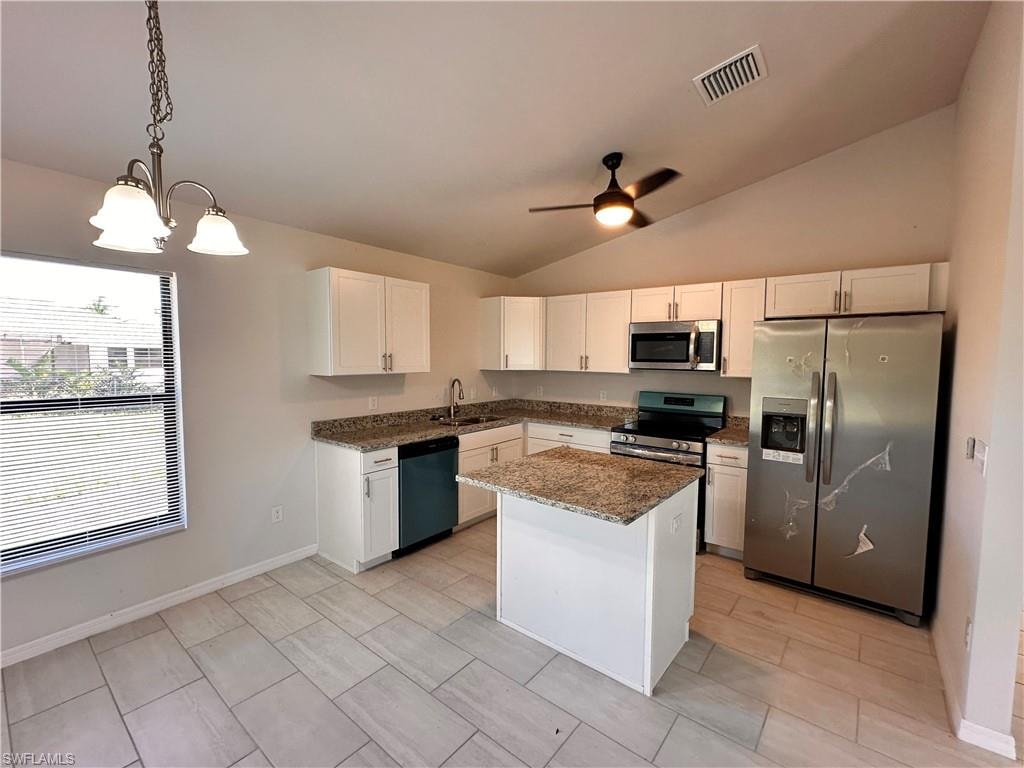 Kitchen featuring stainless steel appliances, dark stone countertops, white cabinets, ceiling fan, and lofted ceiling