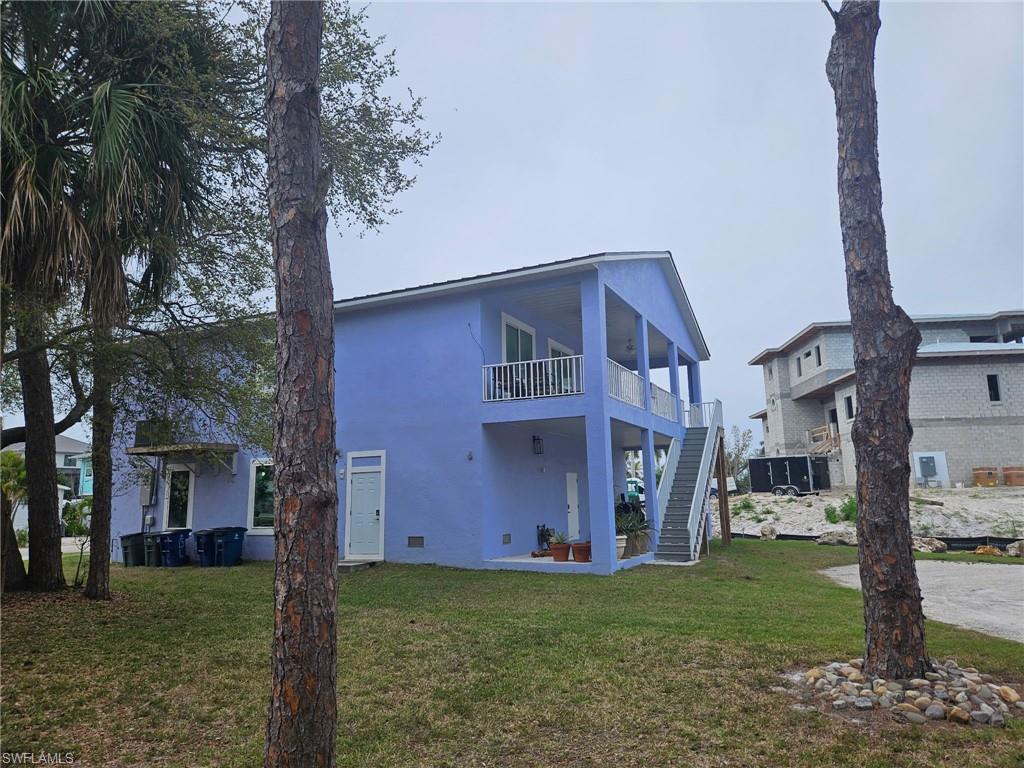 Back of house featuring a patio area, a lawn, crawl space, a balcony, and stucco siding