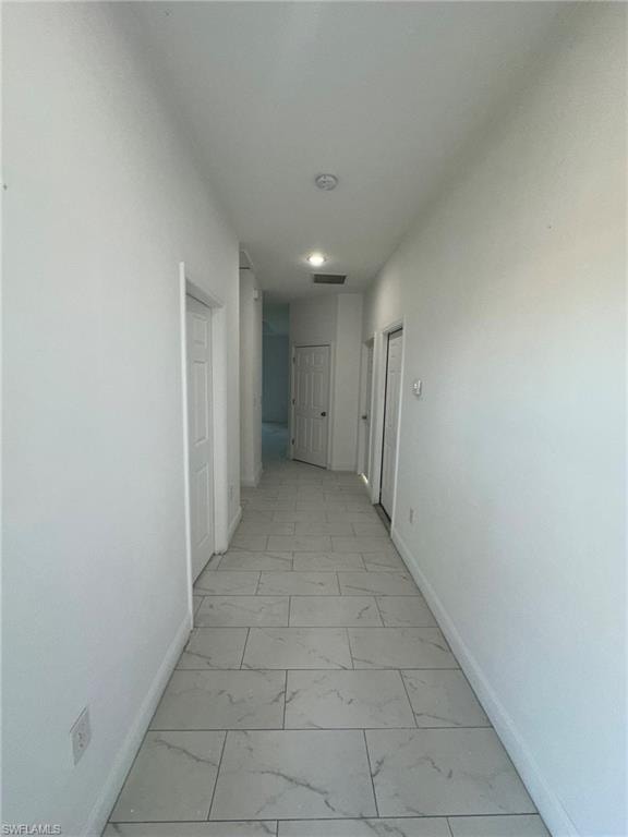 Hallway featuring light marble finish flooring and baseboards