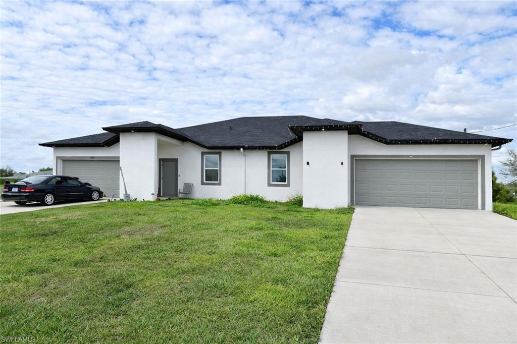 View of front facade featuring a front yard, an attached garage, stucco siding, and concrete driveway
