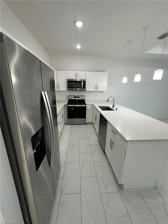 Kitchen featuring stainless steel appliances, light marble finish flooring, a peninsula, white cabinets, and light stone countertops