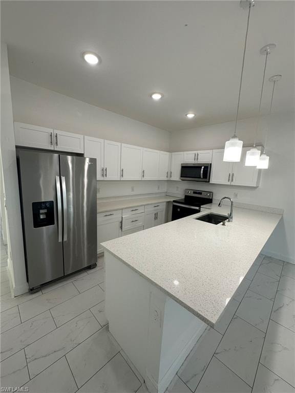 Kitchen featuring light marble finish floors, a peninsula, stainless steel appliances, and white cabinets