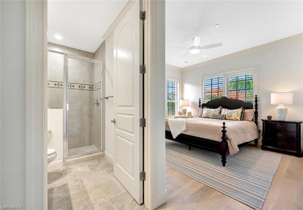 Bedroom with ornamental molding, ensuite bathroom, a ceiling fan, and light wood-style flooring