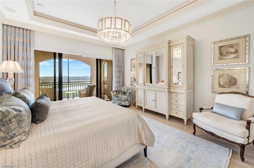 Bedroom featuring crown molding, suspended lighting, a tray ceiling, wood finished floors, and access to outside