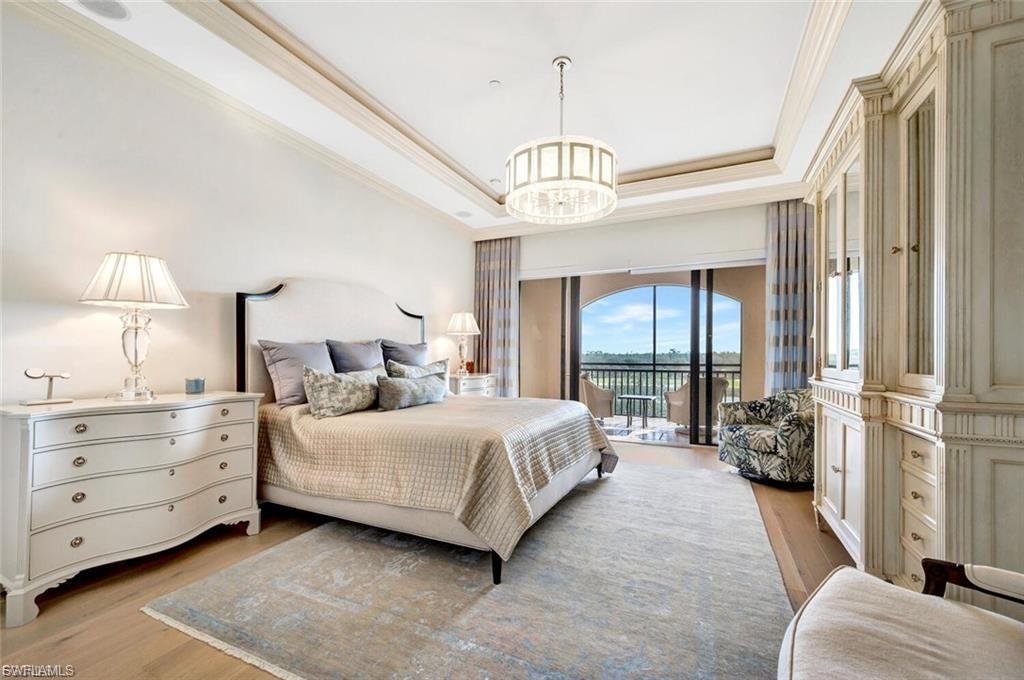 Bedroom with a raised ceiling, light wood-style flooring, access to outside, crown molding, and suspended lighting