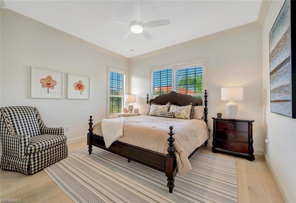 Bedroom with ornamental molding, light wood-style floors, multiple windows, and a ceiling fan