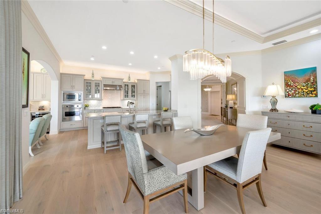 Dining room with arched walkways, crown molding, light wood finished floors, and recessed lighting