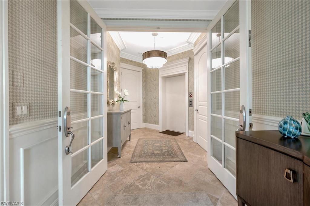 Entryway featuring wallpapered walls, ornamental molding, french doors, and elevator