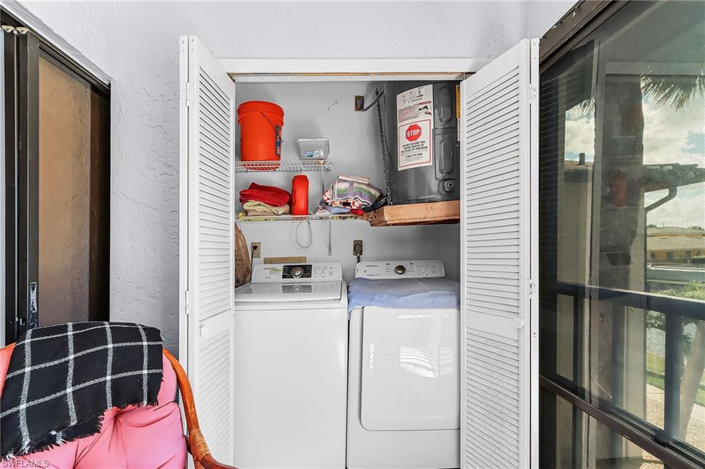 Laundry area with a textured wall, electric water heater, and washing machine and dryer