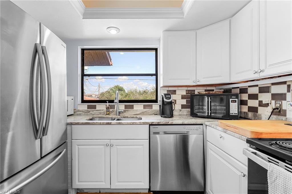 Kitchen featuring stainless steel appliances, white cabinetry, tasteful backsplash, and crown molding