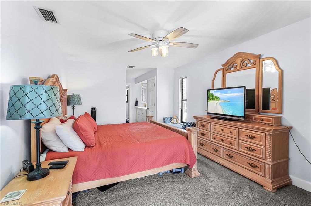 Carpeted bedroom featuring connected bathroom and ceiling fan