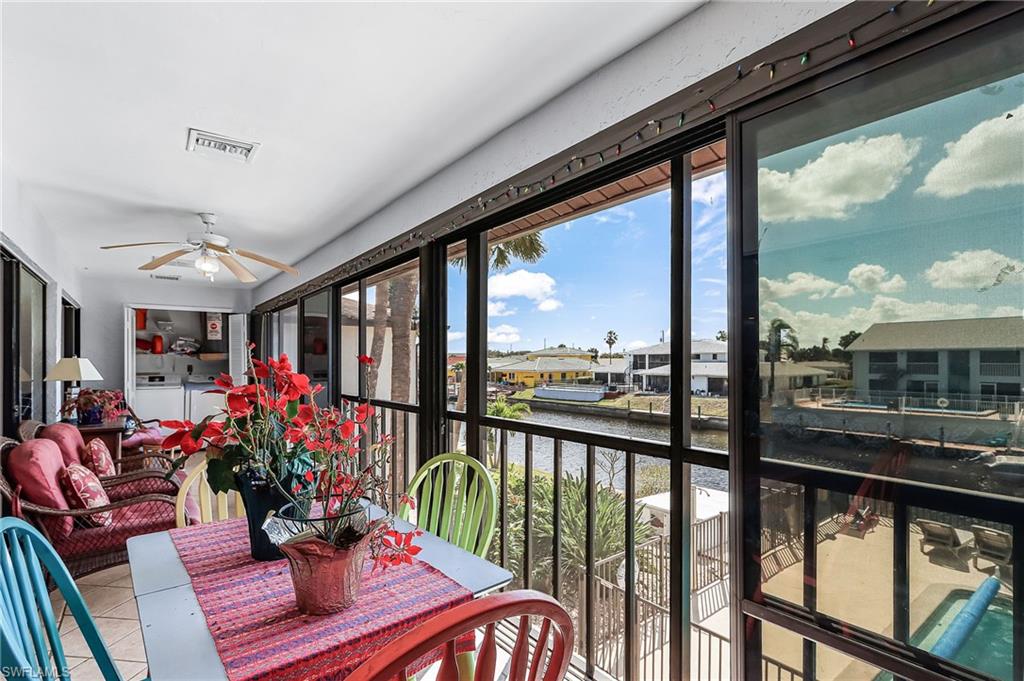 Sunroom with a water view, tile patterned flooring, washer and dryer, and a residential view