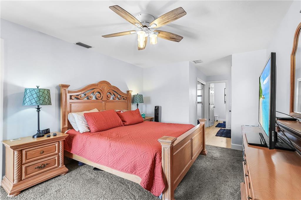 Bedroom featuring dark colored carpet, ensuite bath, and ceiling fan